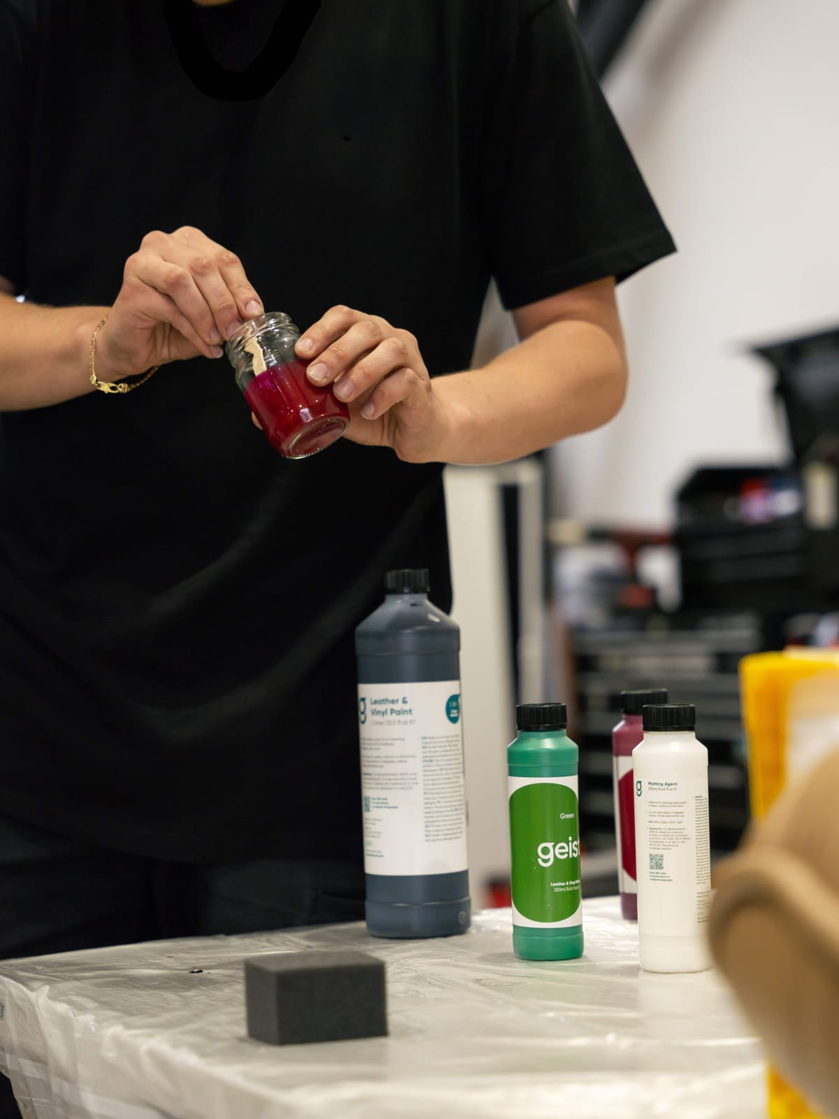 Custom-matched leather dye being blended in a jar alongside Geist paint bottles
